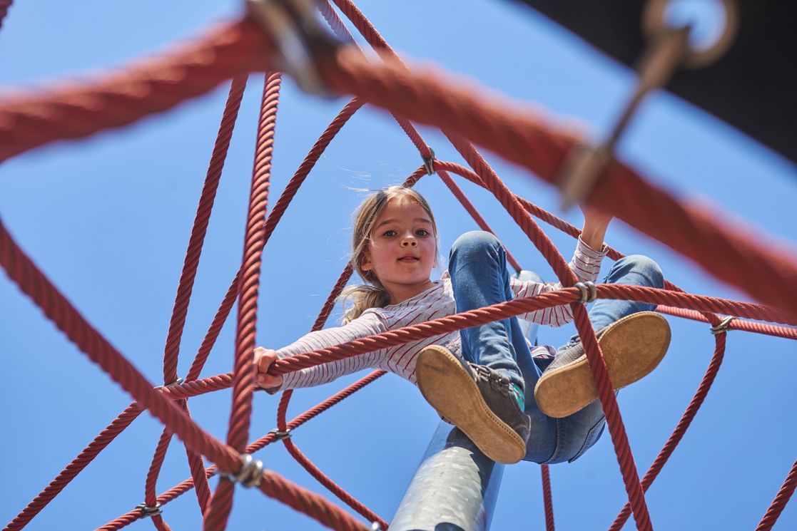 Active young child girl climbing the spider web playground activ aufwachsen_im_landgutviertel